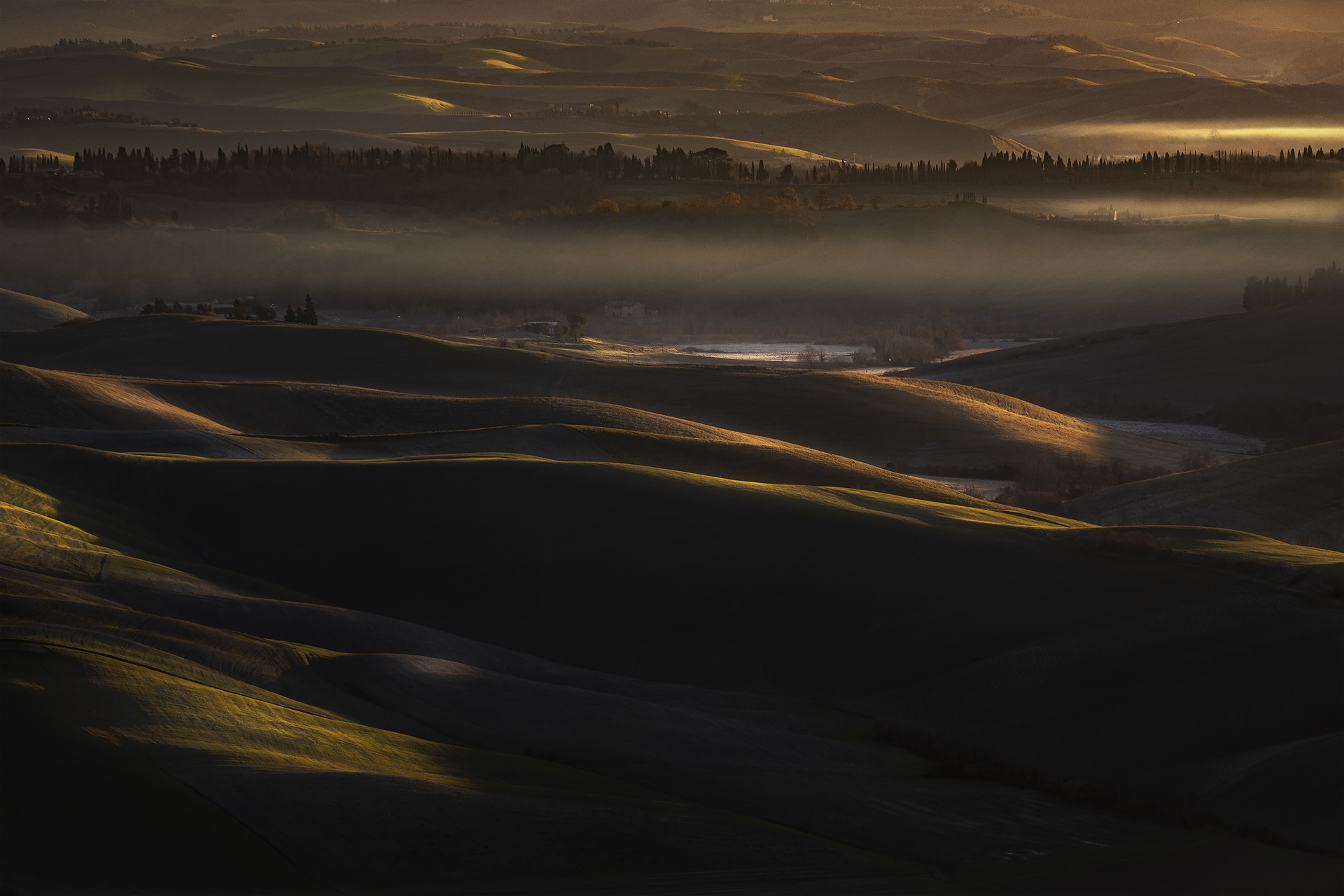 Panorama mattutino delle colline toscane nei pressi di Rivalto, Chianni, Pisa, Italia, con luce radente e nebbie sospese tra i crinali