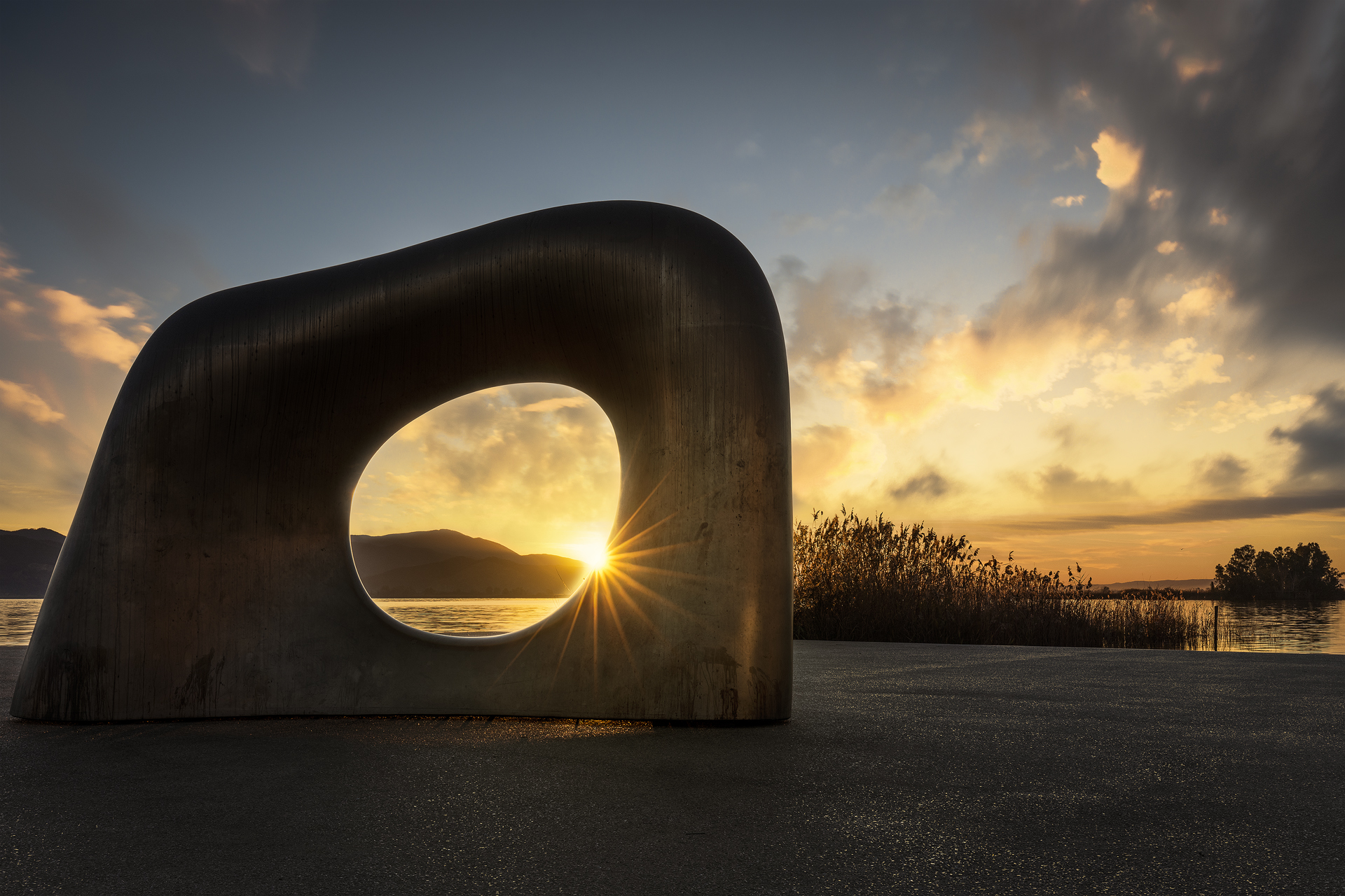 Scultura moderna al tramonto con il sole che filtra al centro, Torre del Lago Puccini, Lago di Massaciuccoli, Toscana, Italia